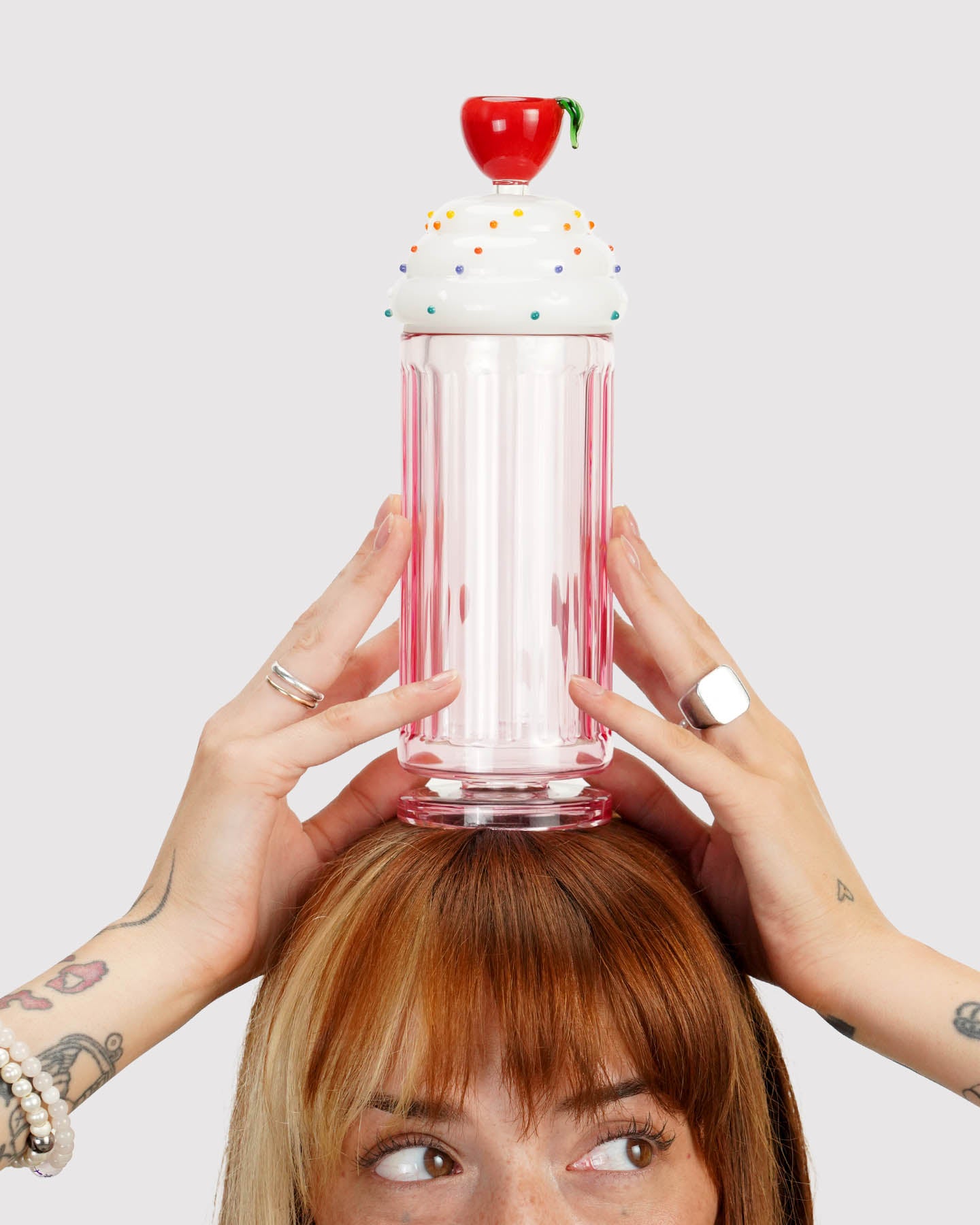 model looking to the side and holding a milkshake gravity bong above their head