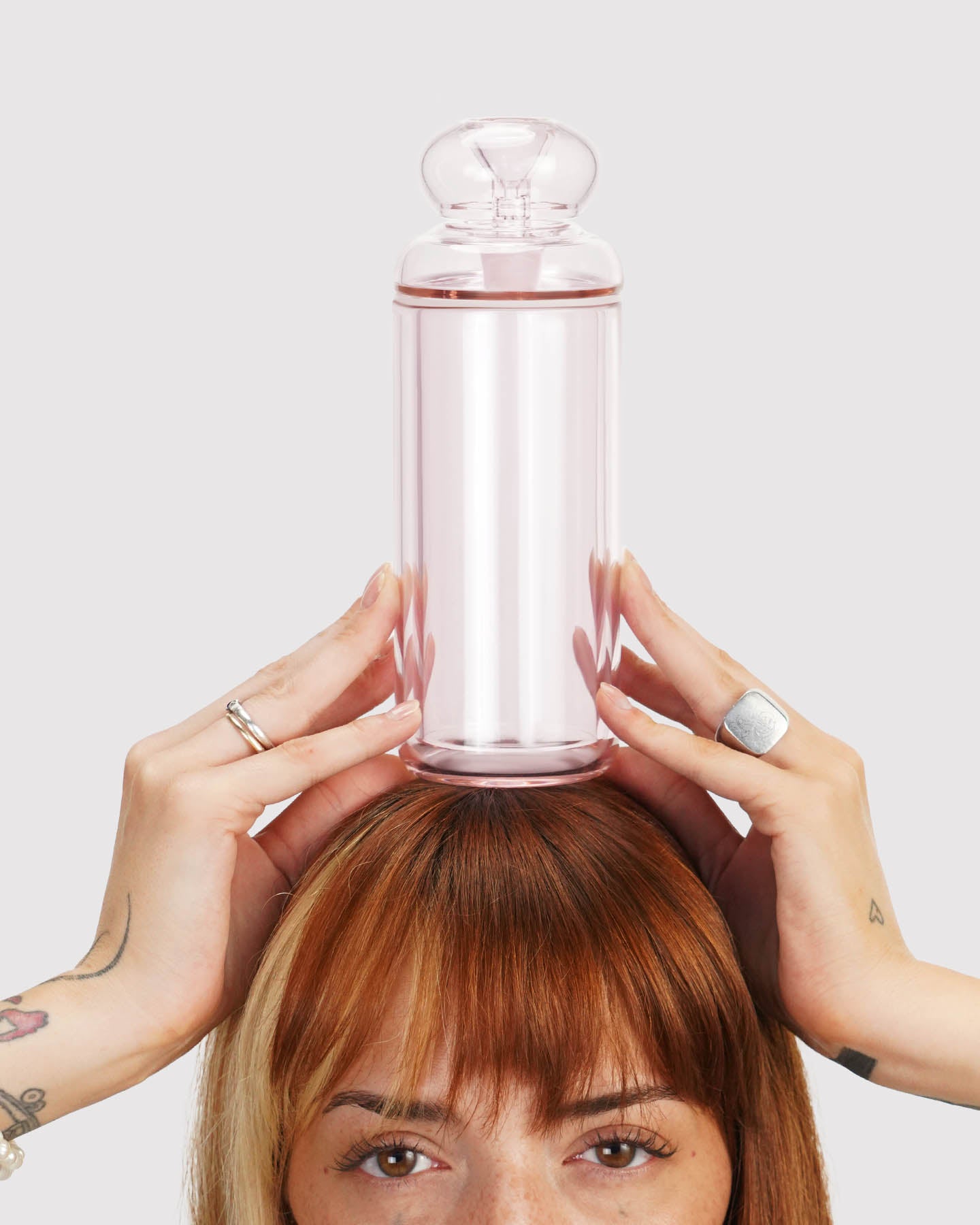 model holding a pink classic gravity bong above her head.