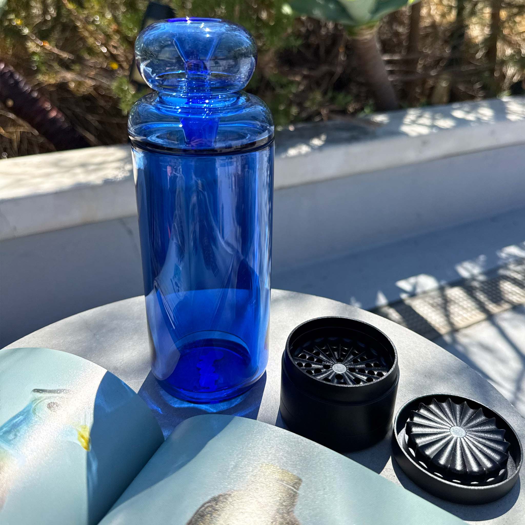 blue glass gravity bong and toothless grinder on table top