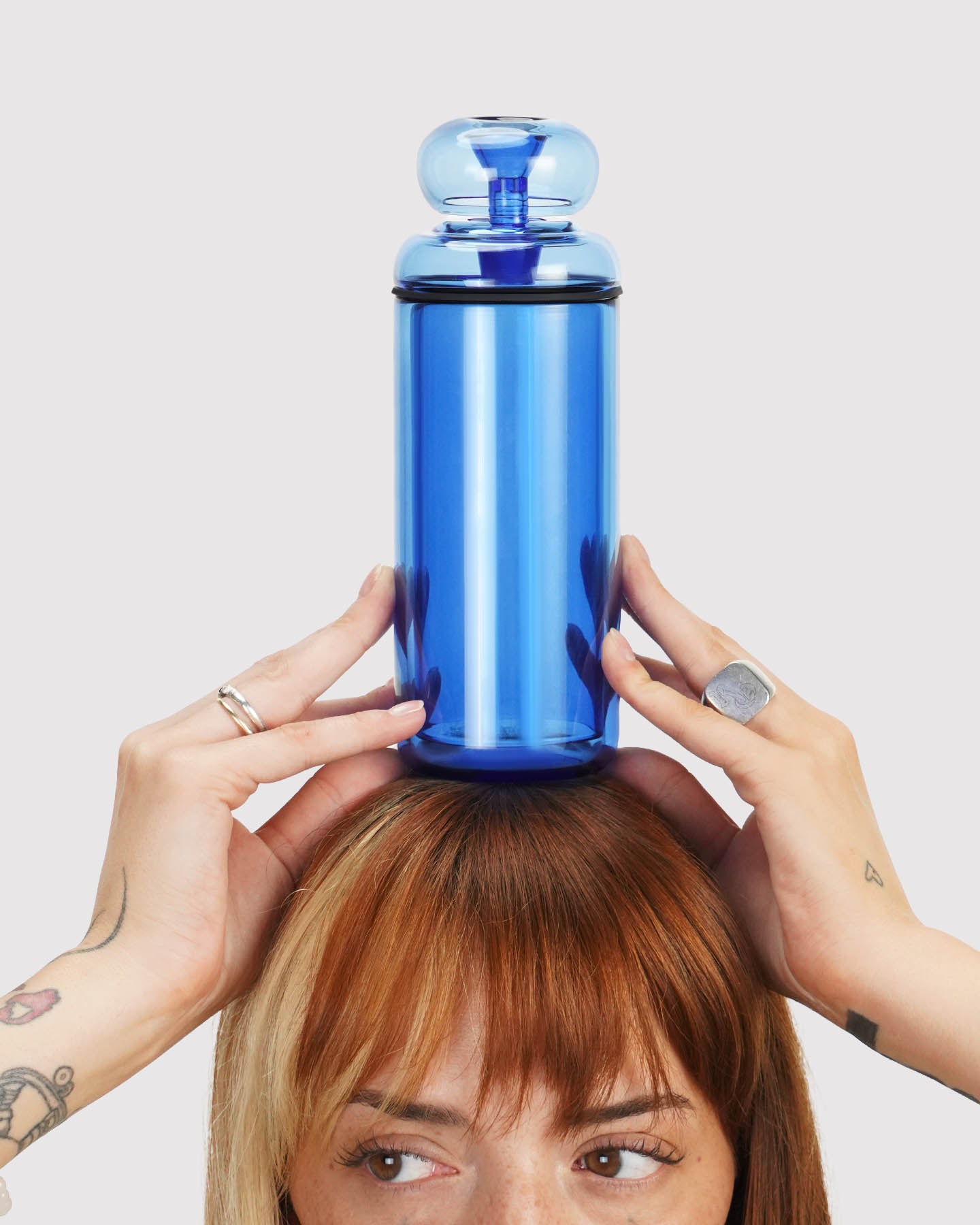 model looking to the side and holding a blue classic gravity bong above their head. 