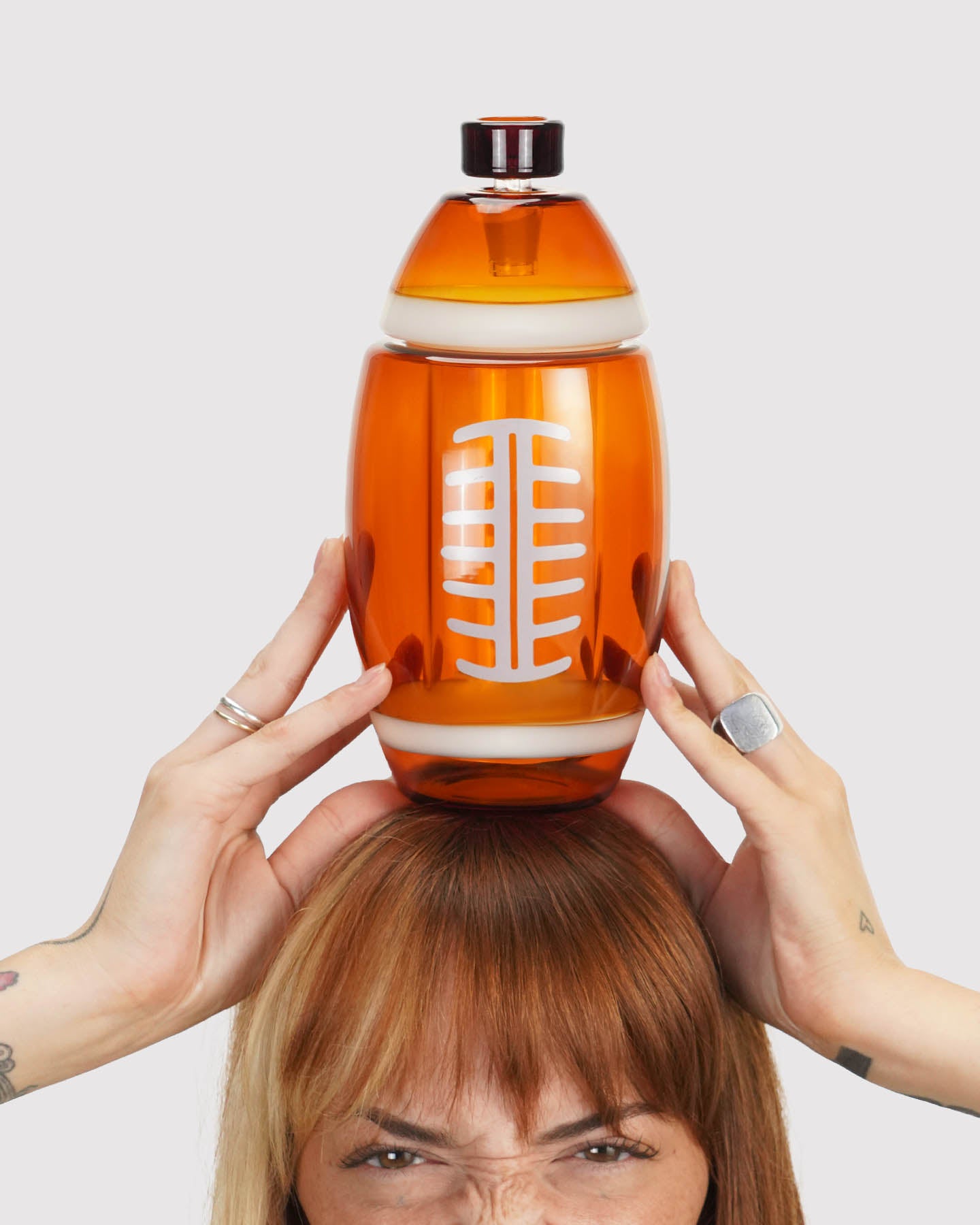 model holding a football gravity bong above her head. 