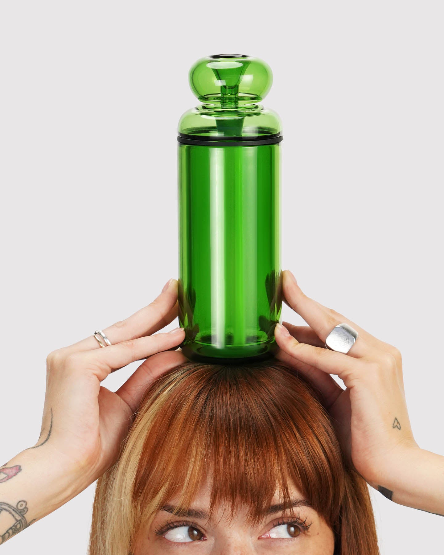 model looking to the side and holding a green classic gravity bong above their head 