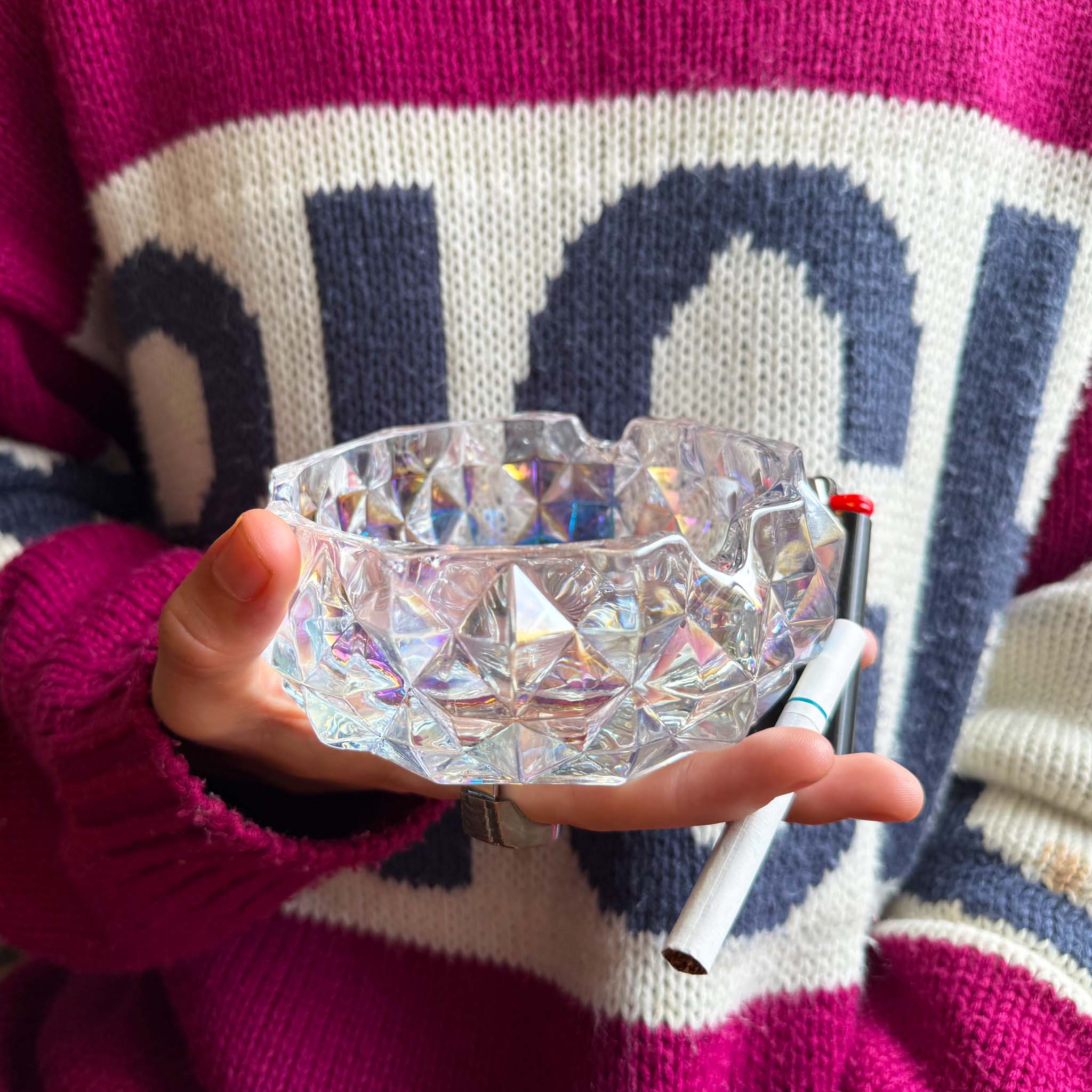model holding iridescent ash tray with cigarette and lighter in hand