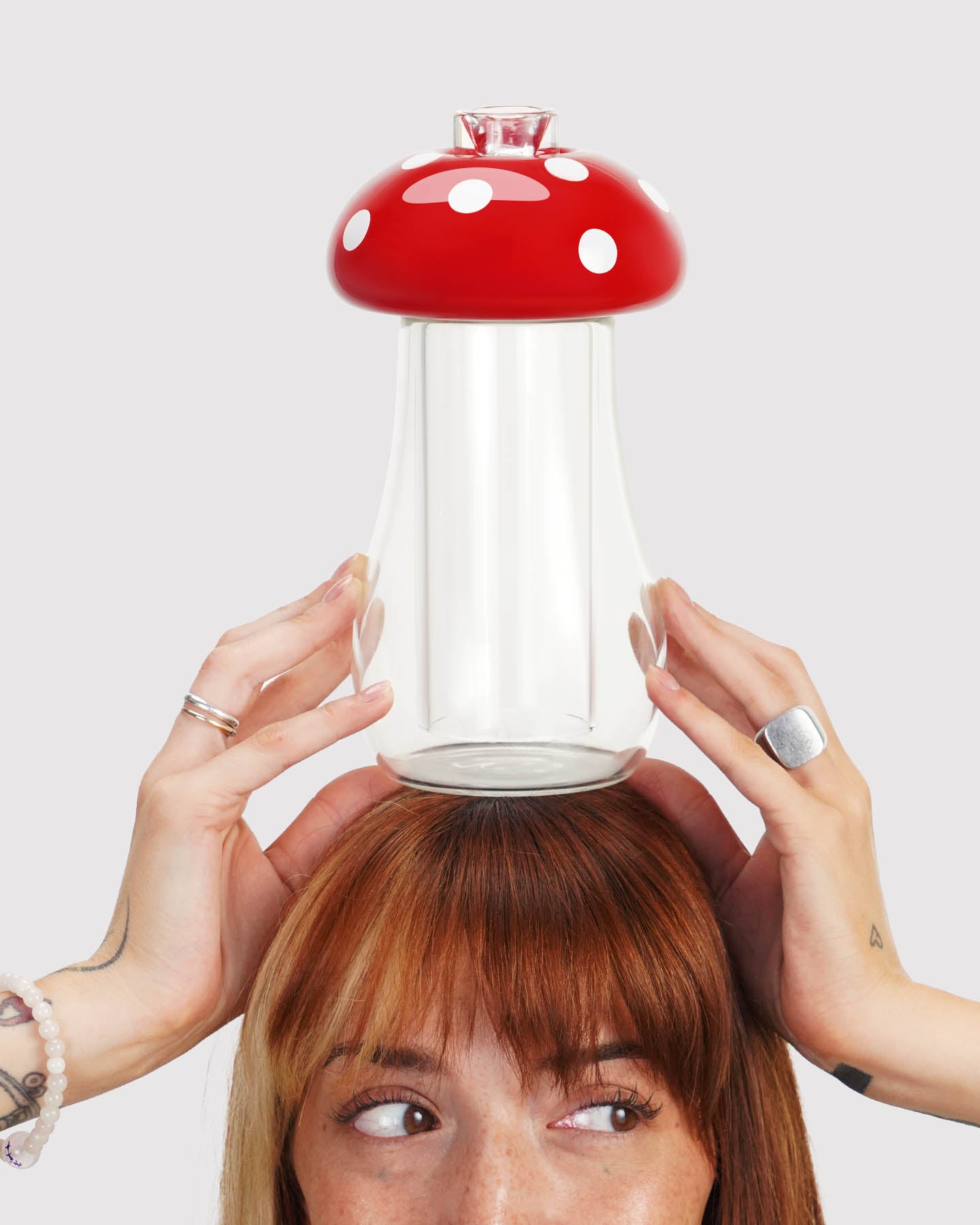 model looking to the side and holding a mushroom gravity bong above their head