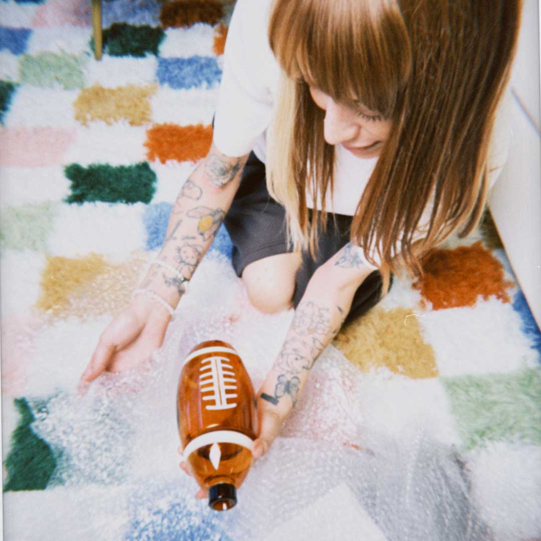 model kneeling on checkered rug opening football gravity bong 